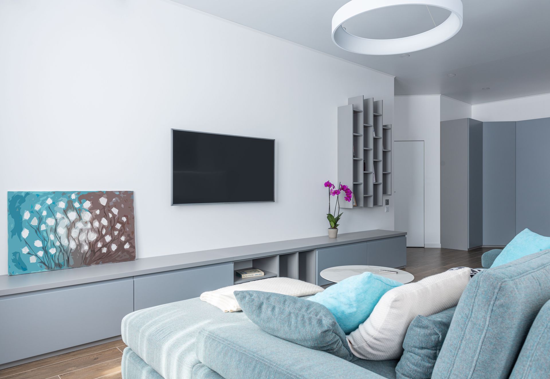 Modern interior of spacious living room decorated with gray shelves purple potted flower and picture