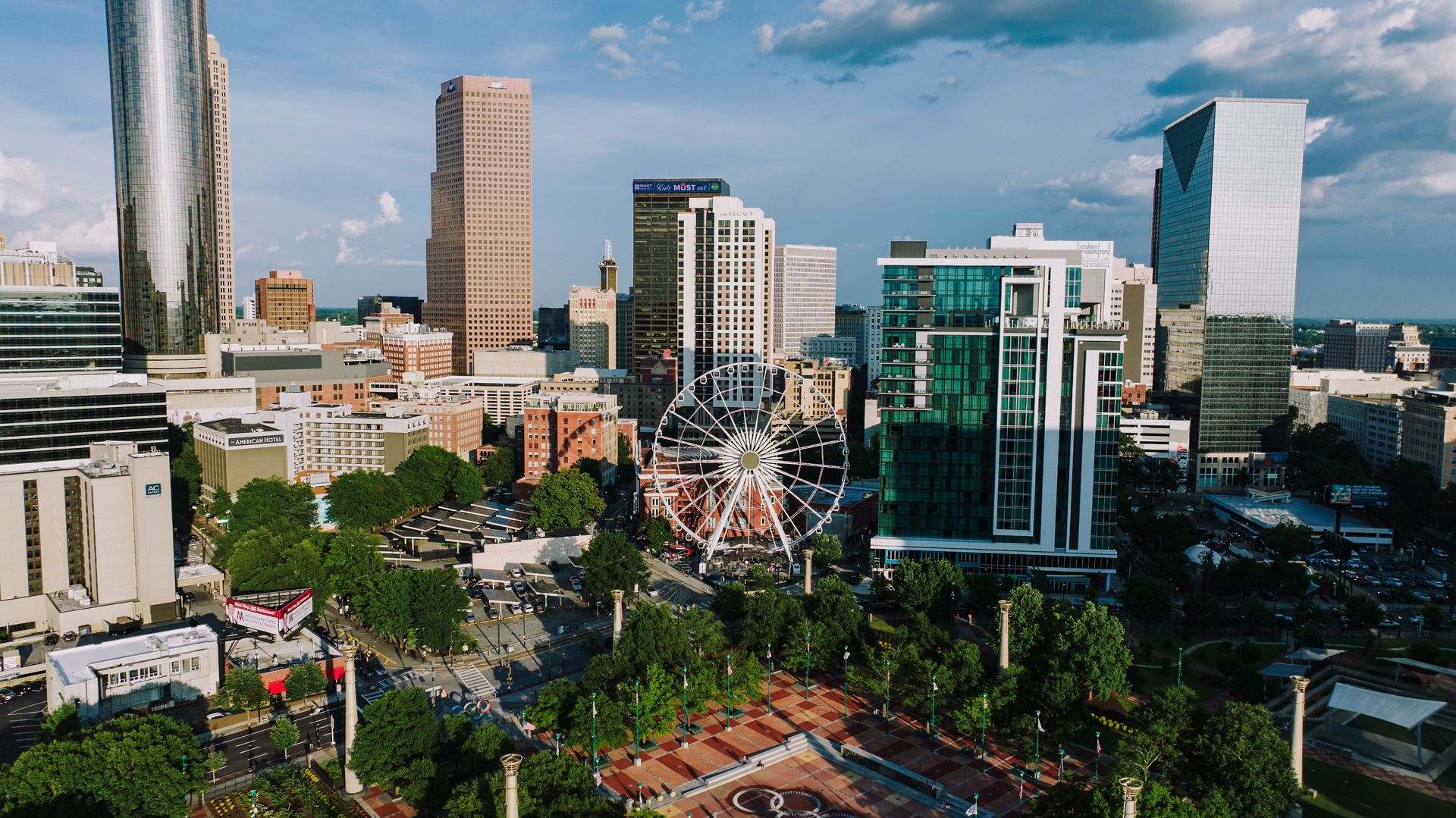 A panoramic view showcasing the vibrant Atlanta skyline with a Ferris wheel in the foreground.