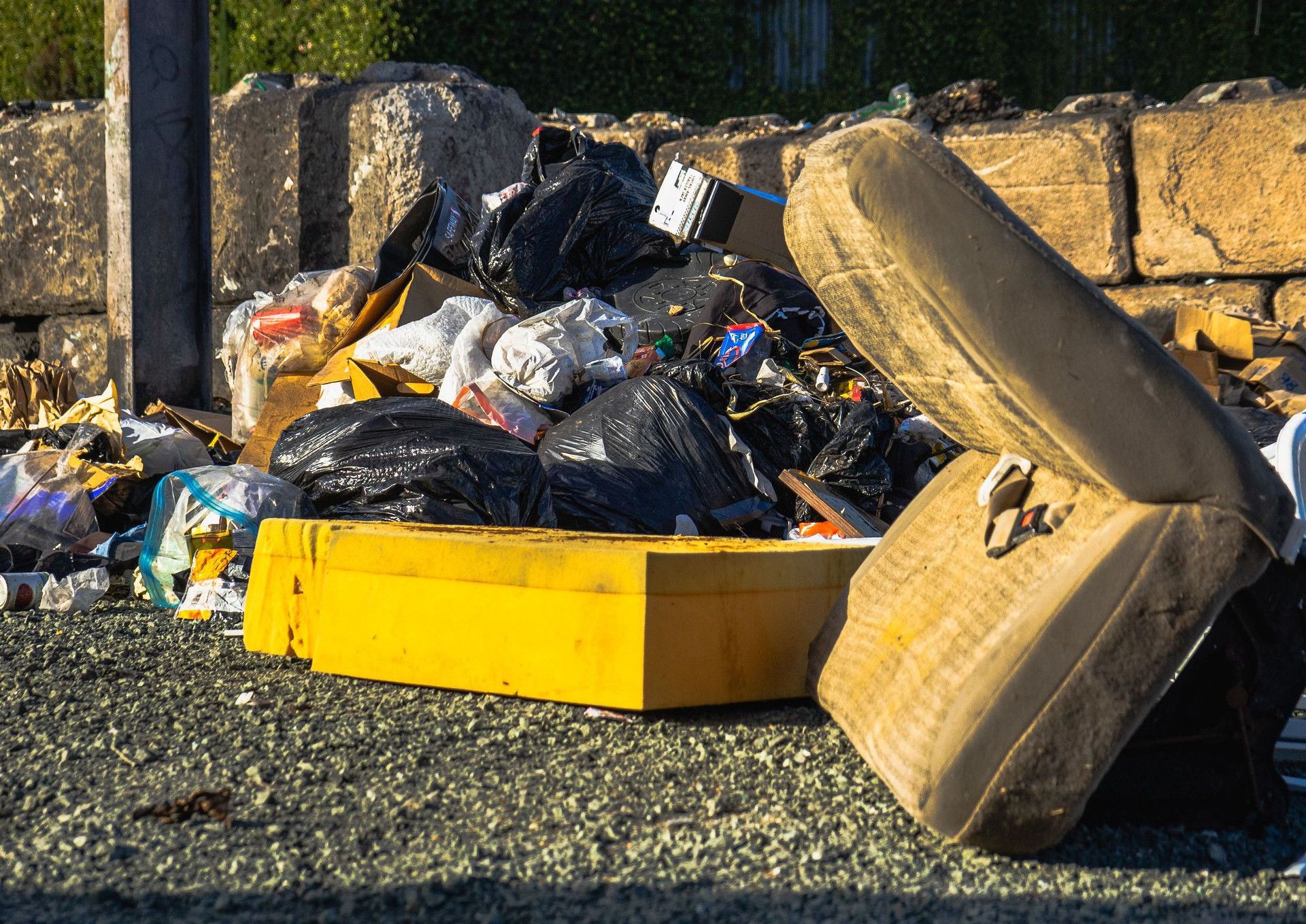 Outdoor scene of a garbage pile including a discarded mattress and various waste materials.